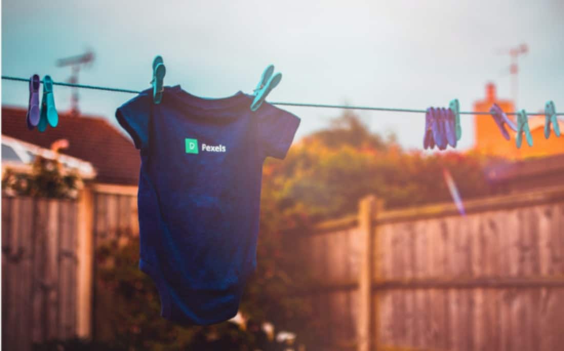 Baby's blauer Körper, der an zwei Wäscheklammern hängend in der Sonne trocknet