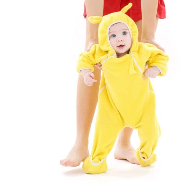 Bébé qui fait ses premiers pas dans une combinaison jaune