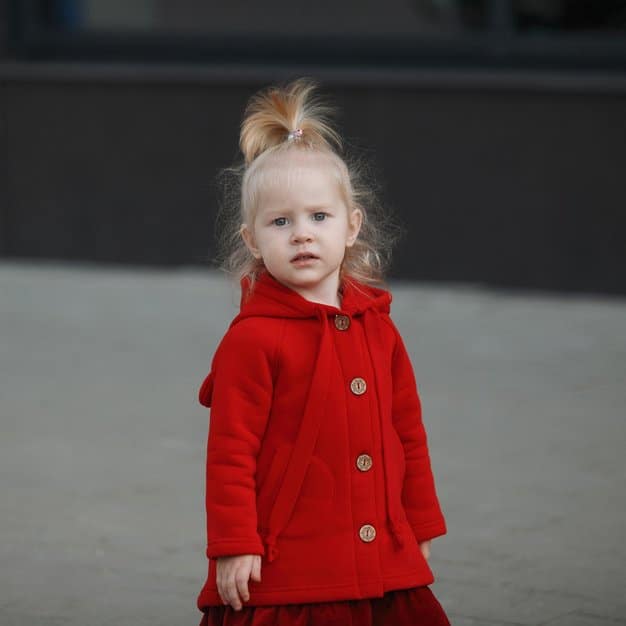 Petite fille qui porte un jolie manteau rouge