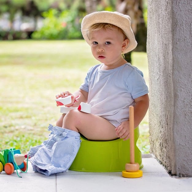 petit bébé assit sur son pot dans le jardin