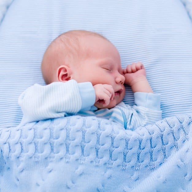 bébé qui dort couvert d'une couette bleu