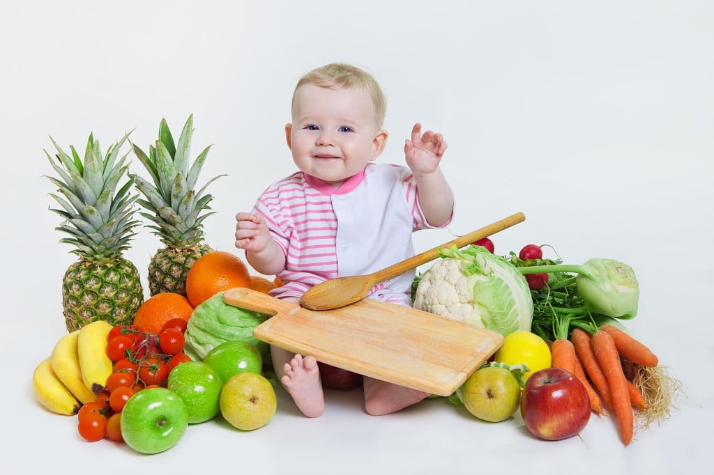 bébé au milieu de fruits et légumes