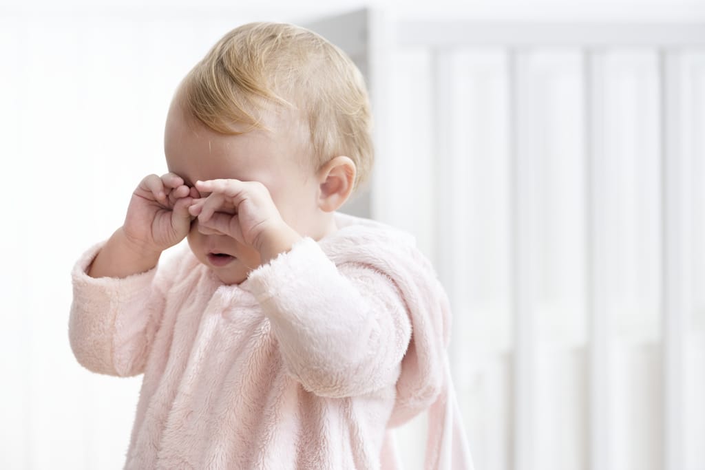 ein ganz in Rosa gekleidetes Kleinkind reibt sich die Augen, um zu signalisieren, dass es müde ist