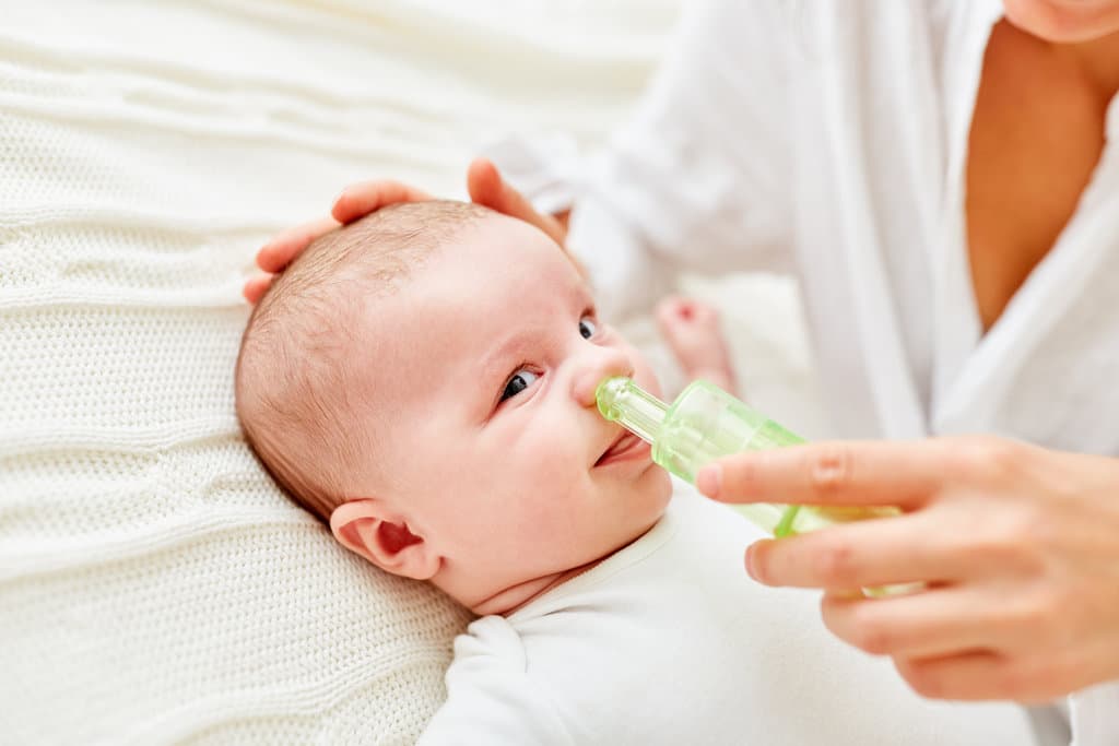 Die Nase eines Babys wird mit einem Nasensauger gesäubert